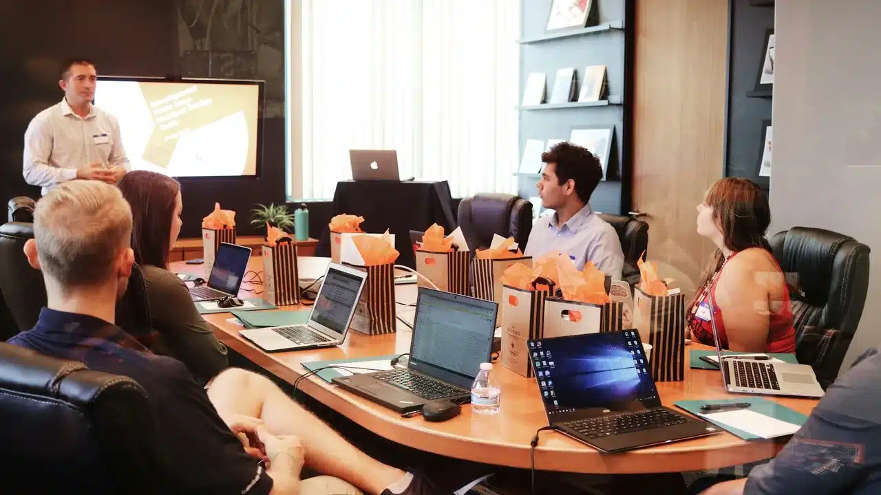 Session de formation en entreprise : un formateur présente devant une équipe équipée d'ordinateurs portables